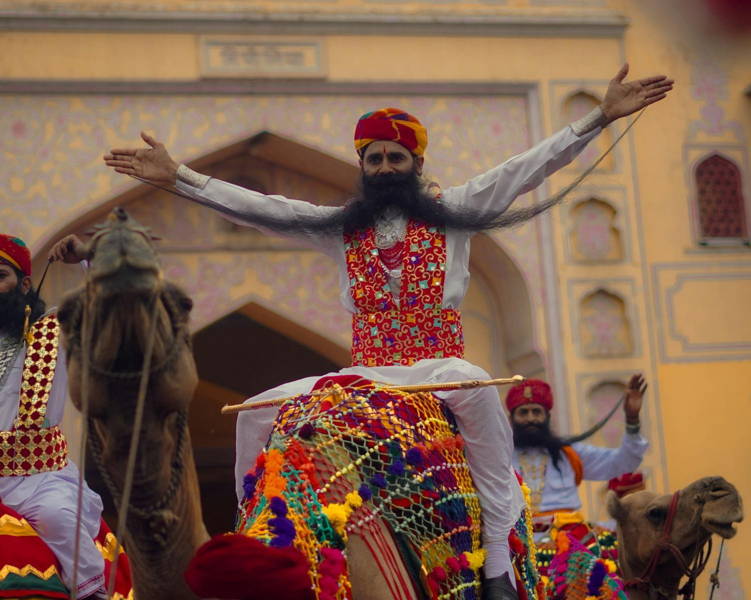 Colorful cultural parade featuring camel riders in traditional attire at a festive event.
